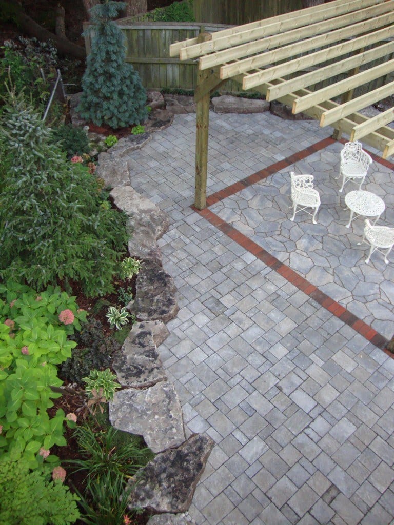 Backyard patio with pergola, stone pavers, and landscaped garden